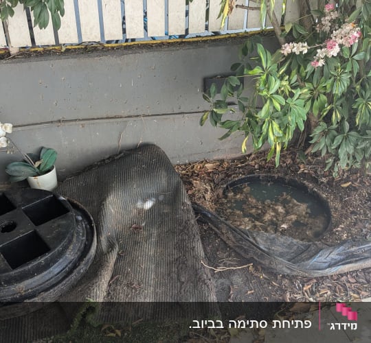 מכסה עגול שחור ליד בור עם מים ולכלוך